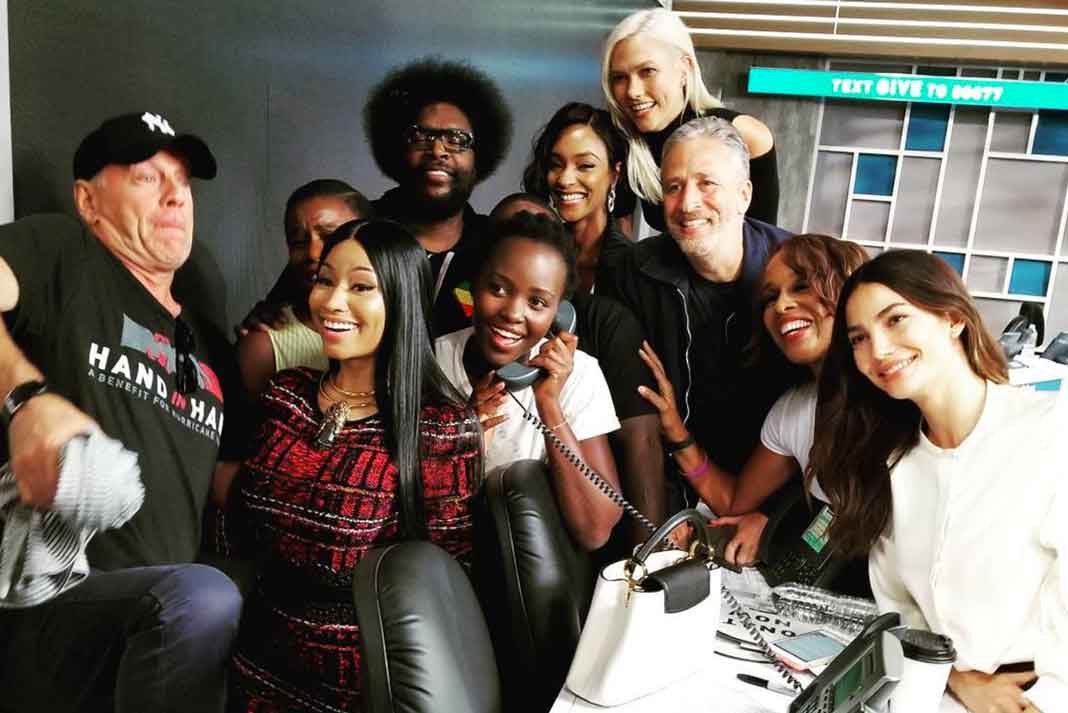 La actriz mexico-keniana Lupita Nyong'o atendiendo el teléfono entre artistas como Bruce Willis y Nicki Minaj