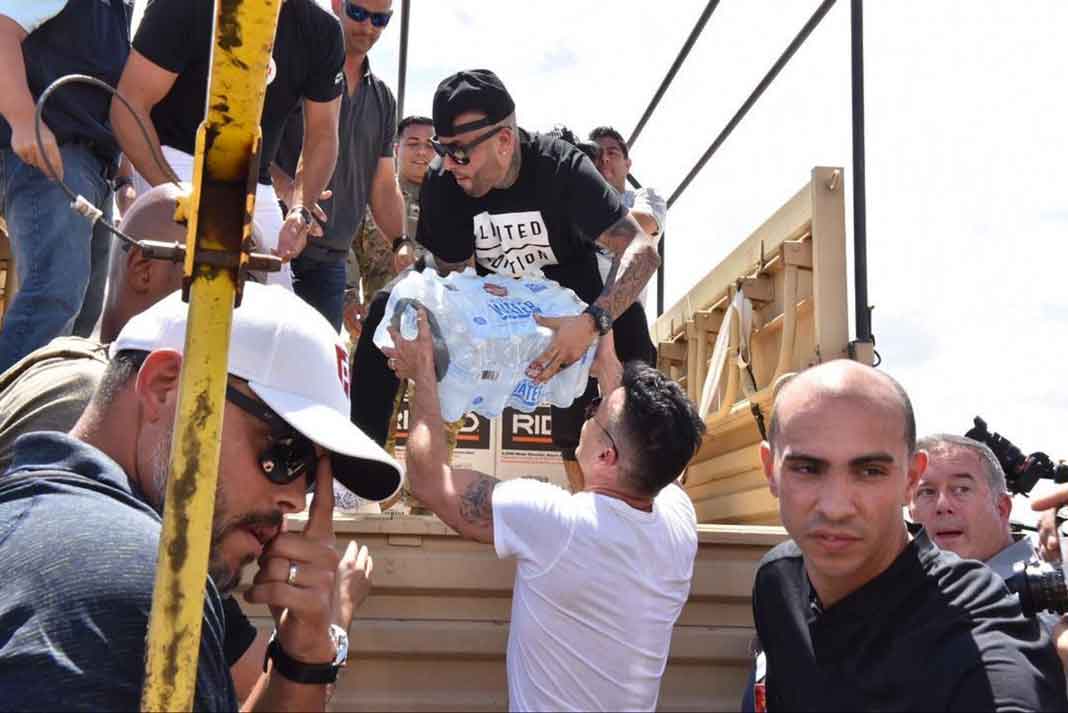 Ricky Martin pasándole el agua y los alimentos que llevaron a Nicky Jam, quien estaba arriba de uno de los camiones que repartiría la ayuda por la isla